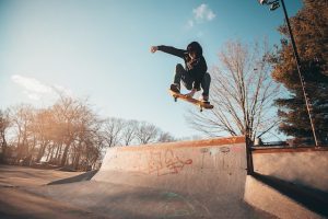 A guy doing a complicated vert trick with his skateboard. 