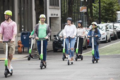 group of friends wearing their helmets as they ride on scooters