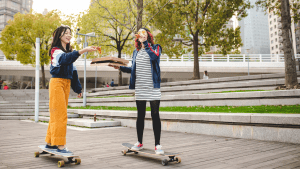 Two girls riding skateboards during spring season. 