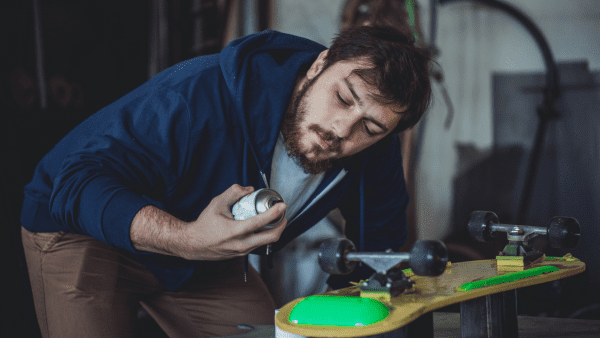 Paint - A man wearing a jacket is painting a skateboard.