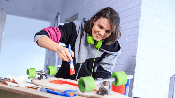 A girl is applying paint to her skateboard