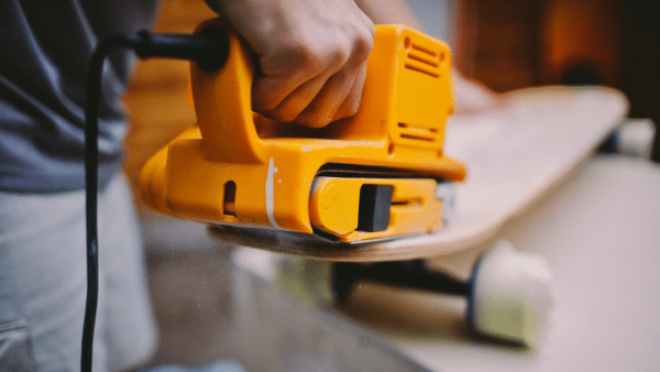 A machine smoothing a skateboard before paint