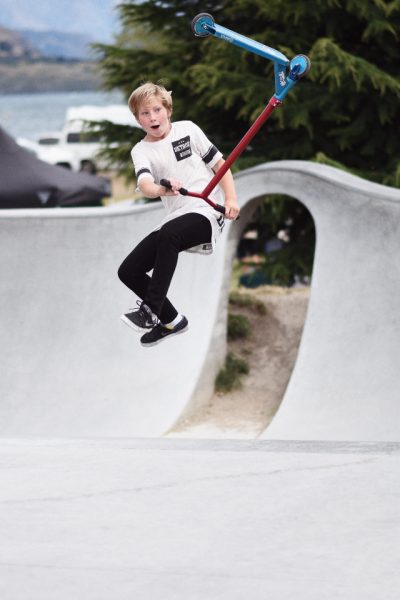 little kid riding and practicing his techniques in the park, looking surprised at his success