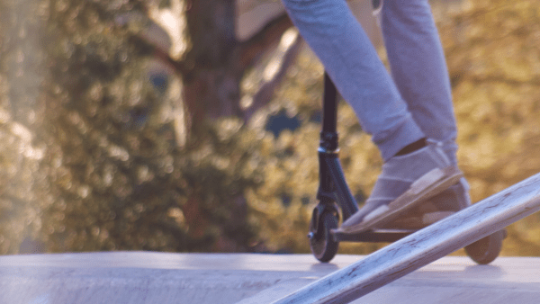 A person wearing gray shoes rides his stunt scooter and ready to show his best tricks. 