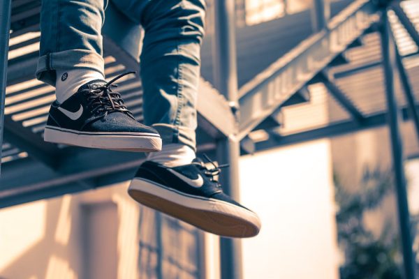 a person in jeans wearing his black skate shoes while taking a much-needed break