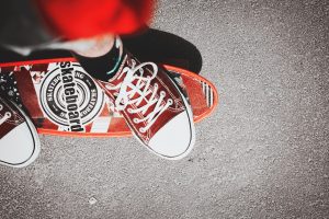 A person wearing a brown and white shoes rides his electric skateboard. 