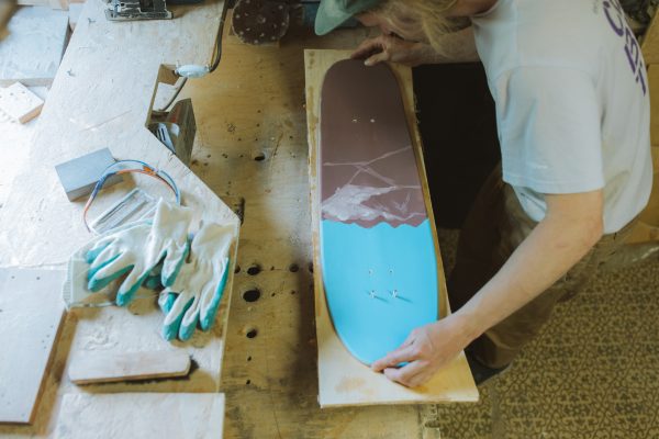 The man in his workplace where he makes longboard. 