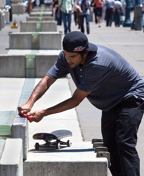 The man is using the skateboard wax 