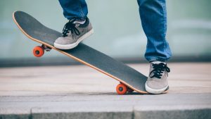 A man confidently stands on a deck, ready to skate down the urban streets.