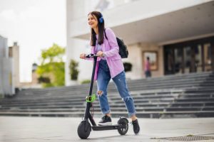 A girl with headphones is riding her scooter