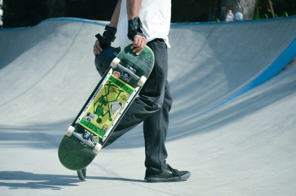 A skateboarder holding a board with clean bearings. Ready to skate with other skaters, Keeping your board clean is essential to a safe skateboarding experience.
