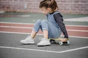 Kid sits on skateboard for toddler