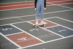 A toddler wearing a white shoes rides her skateboard for practice. 