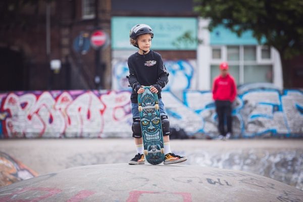 A kid wearing skateboarding gear is resting from his ride.