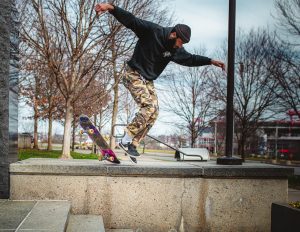 A skateboarder, flying on air, doing tricks with his skateboard 