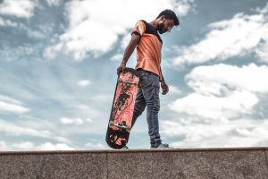 a skateboarder holding a skateboard for skateboarding. The skateboard is his old skateboard, a skateboard gift