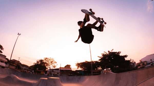 A skateboarding enthusiast performing an advanced skateboard trick mid-air in the skate park in the early morning.