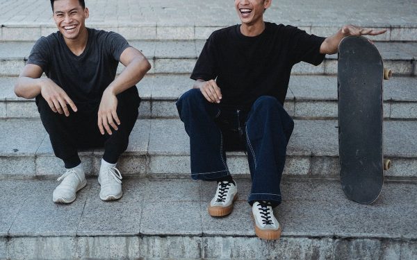 Two guys are laughing as they hold their board.