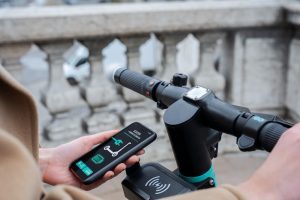 While riding the electric scooter, the person expertly uses their best smartphone to fine-tune the settings, ensuring a safe and enjoyable electric scooter ride. They skillfully navigate the streets, merging the best technology and best transportation.