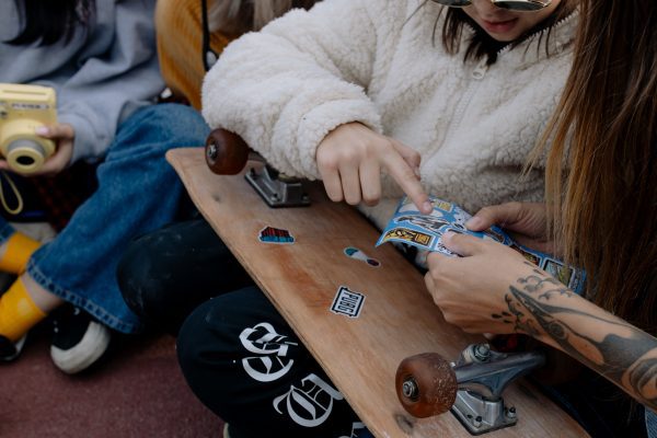 Girls decorating a skateboard.