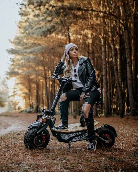 A girl is with her off-road scooter.