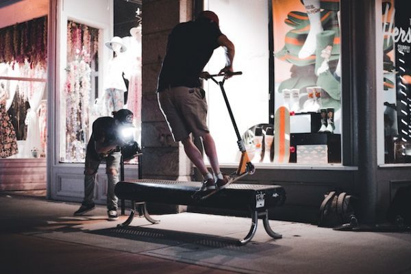 Performing scooter tricks at night in the middle of the street.