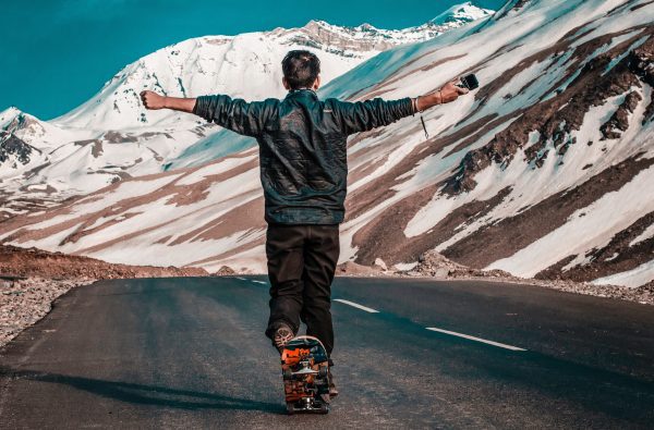 A skateboarder is facing an icy hill while riding a skateboard