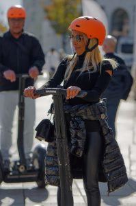 A woman wearing a scooters helmet and scooters sunglasses puts jacket around her waist and smiles while riding one of the greatest scooters.