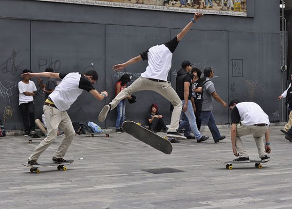 Skateboarders in custom white shirts practicing tricks with custom skateboards.