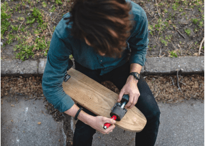 Skateboards: Individual adjusting a skateboard wheel, maintaining the skateboard's wheels.