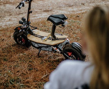 A scooter on a grassy field is equipped with top-notch features that navigates challenging terrains and rugged landscapes. 