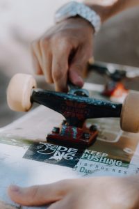 A skater holds the his skateboard deck while fixing the skateboard truck for safe rides.