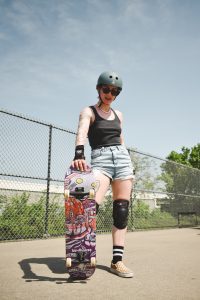 Woman with skateboard protective gear for safe skateboard ride. 