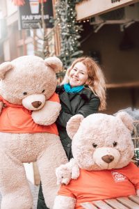 A woman posing with 2 life-size stuffed bears. The two life-size stuffed toy are cute. The woman looks happy while carrying the other lifesize bear. 