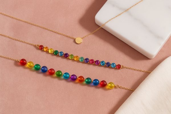 Three chokers\u2014gold pendant, gemstone, and glass bead\u2014arranged on blush velvet with a marble tray and linen napkin.