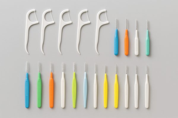 Floss picks and interdental brushes arranged in parallel rows for comparison.