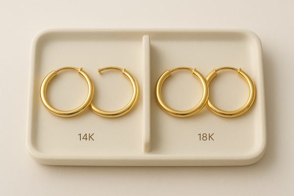 Two pairs of medium gold hoops\u201414K and 18K\u2014side by side on a cream tray, separated for clear comparison.