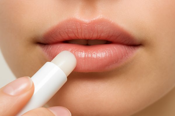 Macro image of clear lip balm being applied to chapped lips, with a focus on the moisturizing effect.