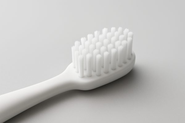 Manual toothbrush with contoured head and micro-bristles for gentle gum care on a seamless grey background.