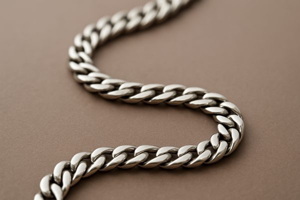 Ultra-high resolution close-up of a men's sterling silver chain on a taupe matte background, showing detail and shine.