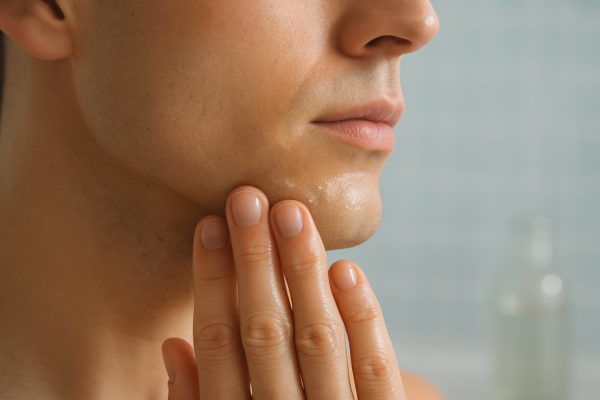 Macro view of soothing oil applied to a freshly shaved jawline, background softly blurred.
