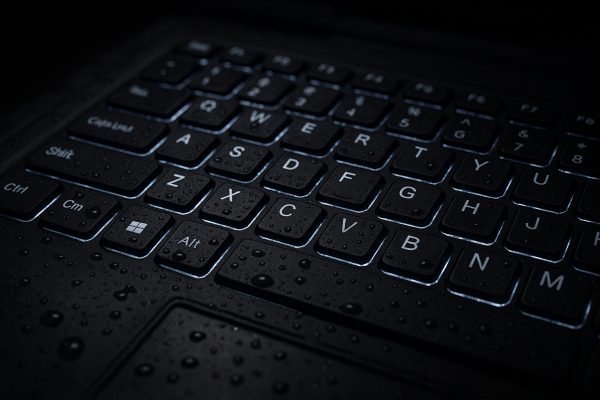 Close-up of waterproof, backlit rugged keyboard with water droplets and tactile keys.