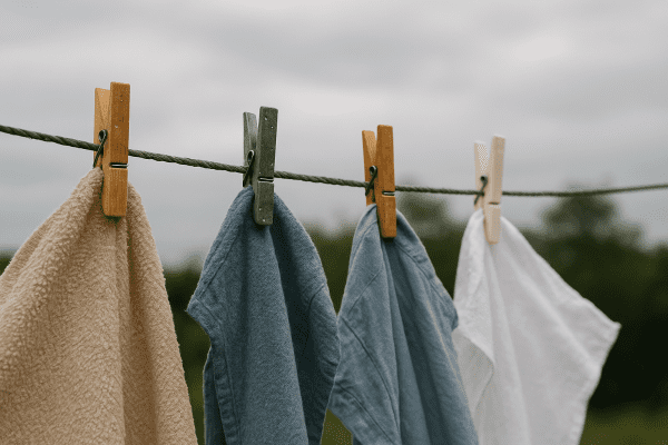 Wooden, steel, and plastic pins hold laundry on a breezy, damp outdoor clothesline.