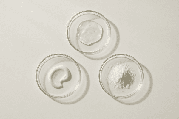 Flat lay of clear glass dishes containing key anti-aging ingredients on a pristine white background.