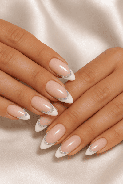 Almond French tip nails with micro-crystal rows and iridescent glitter lines, hands on shimmery white satin.