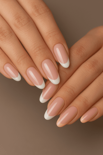 Close-up of hands showing almond and squoval French tip nails with classic and pastel designs.