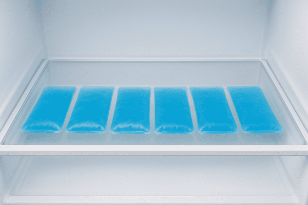 Multiple reusable gel ice packs lined up neatly in an open, frost-free freezer drawer.