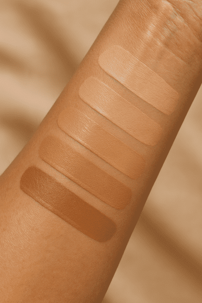 Moisturized mature forearm showing distinct swatches of foundation in various shades and finishes.