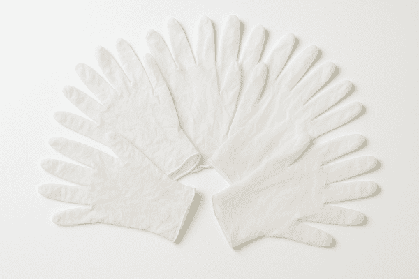 Vinyl gloves, powdered and powder-free, fanned out on a white surface to show clarity and powder residue.