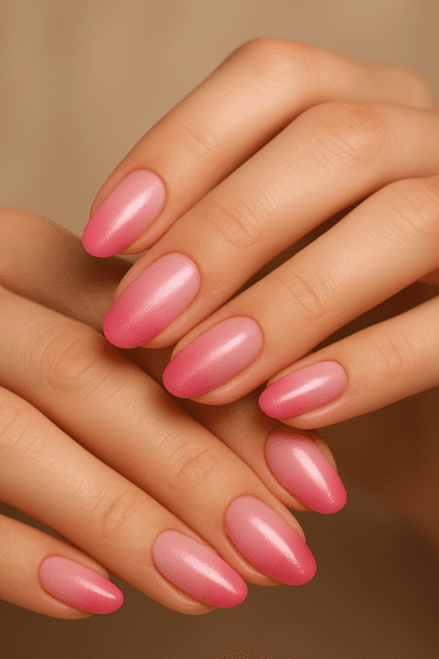 Close-up of manicured hands with a pink ombre gradient and luminous shimmer.